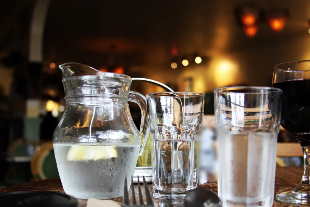 Waterkaraf en glazen op een tafel in een warm verlicht café