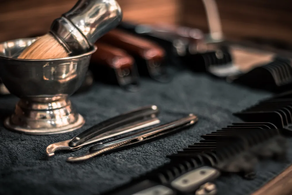 Scheerkwast, scheermessen en opzetkammen op een donkere doek in een barbershop