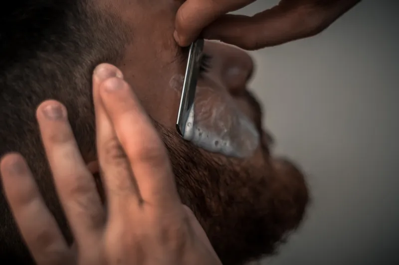 Barbier scheert een baard met een open scheermes