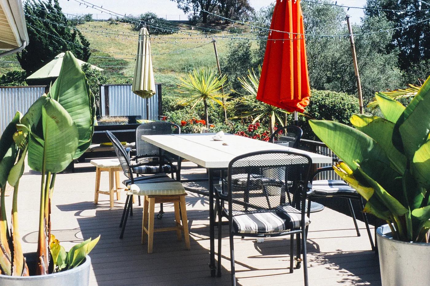 Zonnig terras met tafels, planten en een rode parasol