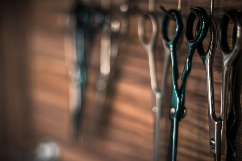 Professionele kappersscharen hangen aan een houten wand