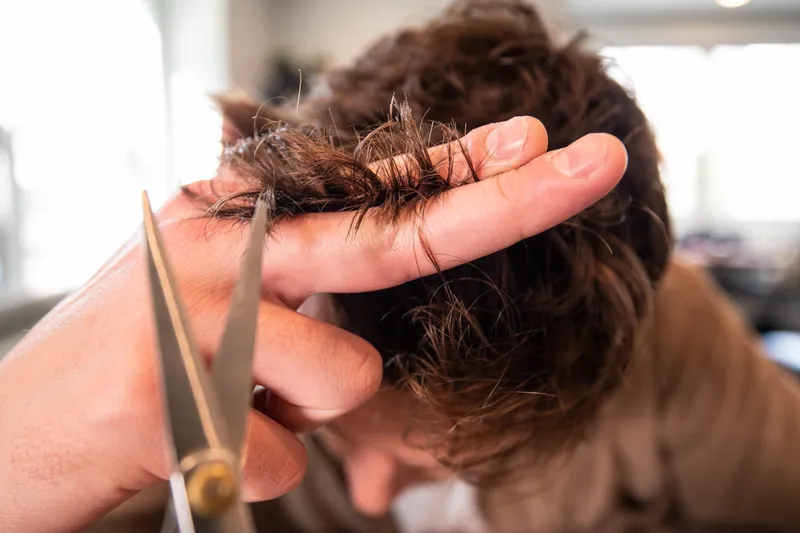 Kapster knipt de punten van kort bruin haar met een schaar
