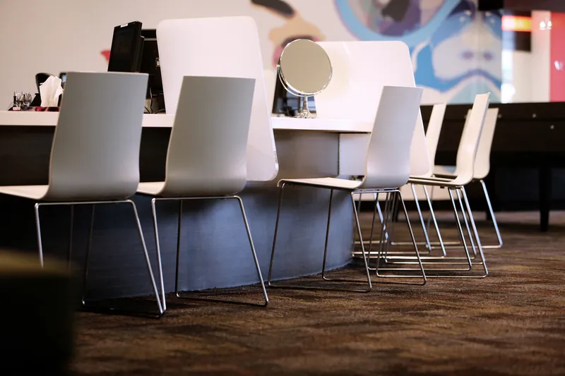 Lege kappersstoelen aan een lange tafel in een lichte salon