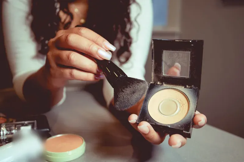 Make-up wordt met een kwast uit een poederdoos aangebracht