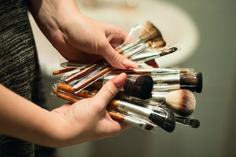 Handen houden een bundel make-upkwasten vast